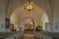 Interior of a protestant church with white arches, illuminated by a large chandelier