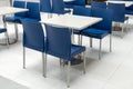 Interior of public dining area with blue plastic chairs and white tables Royalty Free Stock Photo