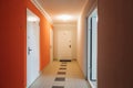 Interior of a residential building in white and orange colors with entrance doors