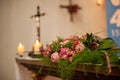 Interior of a Roman Catholic Church with polychrome decoration of the altar and flowers, with an out of focus cross with Royalty Free Stock Photo