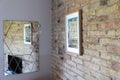 Interior of a room with exposed brick wall and mirror reflecting picture and light bulb hanging on the wall