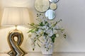 Interior room lamp vase with flowers and a decorative mirror on a light wall Royalty Free Stock Photo