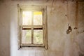 Interior of a ruined house with old, dirty and cracked white wall and a broken window frame with a green meadow field view Royalty Free Stock Photo
