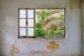 Interior of a ruined house with old, dirty and cracked white wall and a broken window frame Royalty Free Stock Photo