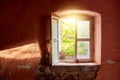 Interior of a ruined old cottage with a light pink wall and a broken wooden window frame viewing a rural green meadow field Royalty Free Stock Photo