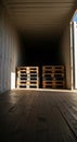 Interior of a shipping container with stacked wooden pallets illuminated by sunlight creating shadows on wooden flooring Royalty Free Stock Photo