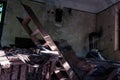 Interior shot of a damaged bedroom, featuring an unmade bed with rumpled sheets and blankets