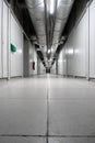 Interior shot of long empty corridor in industrial building with thick thermal pipes on running along the ceiling Royalty Free Stock Photo