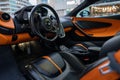 Interior of a sleek black and orange McLaren supercar with leather seats and metallic accents