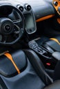 Interior of a sleek black and orange McLaren supercar with leather seats and metallic accents