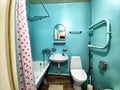 The interior of a small, modest bathroom with a bath and a toilet. Green walls, curtains with a red dot. The concept of