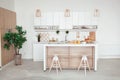 Interior of small white kitchen with fresh fruit, two glasses of orange juice, baguette, red caviar, croissant and