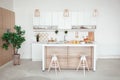 Interior of small white kitchen with fresh fruit, two glasses of orange juice, baguette, red caviar, croissant and