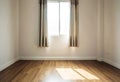 Interior space, empty room, laminate wooden floor with opened window receiving sunlight in the morning Royalty Free Stock Photo