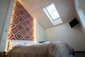 Interior of a spacious hotel bedroom on attic floor with fresh linen on a big double bed. Cozy contemporary mansard room in a