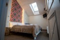 Interior of a spacious hotel bedroom on attic floor with fresh linen on a big double bed. Cozy contemporary mansard room in a