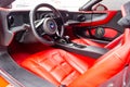 Interior of a sports car Marussia B1 of red color with elegant leather seats, low seating position and steering wheel of a