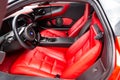 Interior of a sports car Marussia B1 of red color with elegant leather seats, low seating position and steering wheel of a