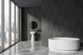 Gray bathroom interior with round bathtub and sink