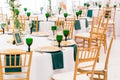 Interior of tent for wedding dinner, ready for guests. Served round banquet table. Golden dishes, green wine glasses and Royalty Free Stock Photo