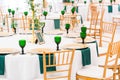 Interior of tent for wedding dinner, ready for guests. Served round banquet table. Golden dishes, green wine glasses and Royalty Free Stock Photo