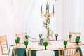 Interior of tent for wedding dinner, ready for guests. Served round banquet table. Golden dishes, green wine glasses and Royalty Free Stock Photo