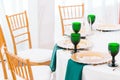 Interior of tent for wedding dinner, ready for guests. Served round banquet table. Golden dishes, green wine glasses and Royalty Free Stock Photo