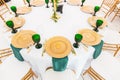 Interior of tent for wedding dinner, ready for guests. Served round banquet table. Golden dishes, green wine glasses and Royalty Free Stock Photo