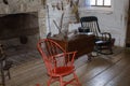 Interior of a traditional 1800s log cabin featuring red and black rocking chairs