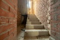 Interior of unfinished brick house with bare walls ready for plastering and concrete stairs prepared foe ceramic tiles cover