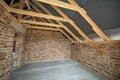 Interior of unfinished brick house with concrete floor, bare walls ready for plastering and wooden roofing frame attic under