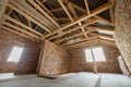 Interior of unfinished brick house with concrete floor, bare walls ready for plastering and wooden roofing frame attic under Royalty Free Stock Photo