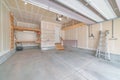 Interior of an unfinished garage with wooden shelving units and stairs to a white door Royalty Free Stock Photo