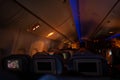 Interior view of a commercial airplane cabin with passengers and blue mood lighting at night Royalty Free Stock Photo