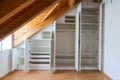 Interior view of a custom-made closet with open doors built into a master bedroom with a sloping roof Royalty Free Stock Photo