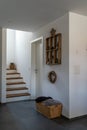 Interior view of an elegant hallway and stairs with black tile floor and white plaster walls and wooden furniture and decorative