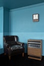 Interior view of old black vintage leather armchair and antique wooden radio receiver box on blue wall background Royalty Free Stock Photo