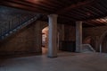 Interior view of an old building with columns and stairway with some light beams in dark surrounding