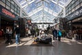 Interior view of shopping centre showing shop fronts, customers and seating area