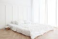 Interior view of unmade messy bed on a wooden floor in the morning with curtain and sunlight Royalty Free Stock Photo