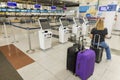 Interior view of woman sitting on carry-on bag in front of baggage drop-of sign in airport. New York. U.S.A.