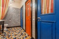 Interior of vintage style toilet room with old wooden doors to bathroom. Blue and red doors over colorful floor tiles Royalty Free Stock Photo