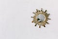Interior wall mirror in the shape of a sun with metal brass sun rays as the frame isolated on white rustic wall Royalty Free Stock Photo