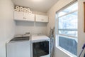 Interior of a white laundry room with cabinets and window