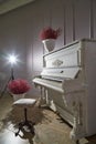 Interior with white piano, bouquets of red flowers and flash like a star. A mysterious and romantic evening. Location