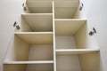 Interior of white plastic cabinet or clothing wardrobe with many empty shelves with open doors. Furniture design and installation