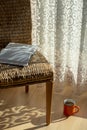 Interior with wicker chair, curtains, book and morning coffe. Design home decor. Sunny morning.