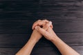 Interlocked fingers, white male hands interlocked on black rustic wood table close up. top view. a man is waiting for negotiations Royalty Free Stock Photo