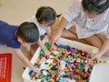 Interlocking plastic bricks in mother`s hands being built with help from her two little babies Royalty Free Stock Photo