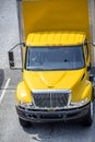 Intermediate rig yellow semi Truck with box trailer running on the road